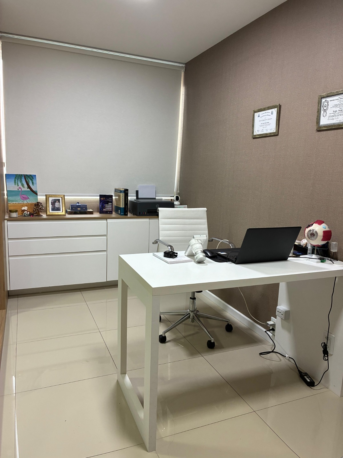 Sala de atendimento da Dra. Regina Sakamoto com mesa e diplomas